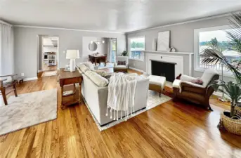 Spacious living room with rich oak floors, log burning fireplace, crown molding, full west wall of windows that offer so much natural light and east facing windows for morning sun and territorial views!