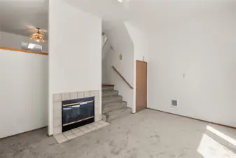 Woodburning fireplace in living room. Stairs lead to dining room and kitchen.