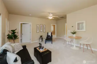 Open concept living room with large windows and ceiling fan