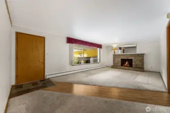 Front entry way and living room with wood burning fireplace. Fireplace in unknown condition, flames a simulation.