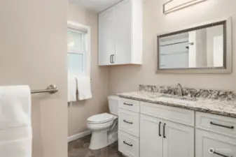 Guest bath was recently remodeled and has newer flooring, toilet, vanity, cabinets, mirrors, lighting, sink and faucet. A full-length mirror (unseen here) hides a secret closet which houses the hot water heater and extra storage.