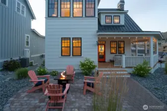 Exterior twilight view of home entrance and outdoor fire pit and outdoor living area.