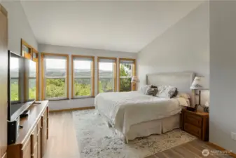 Large primary bedroom with several windows,  The view from the windows is a totally unobstructed view of Mt. Rainier.  Just imagine waking up in the morning to see Mt. Rainier in all of its glory and various moods.