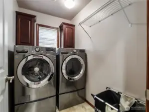 Convenient upper level laundry room with front loading washer & dryer, cabinets and hanging rack.