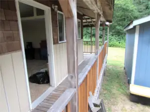 Covered walkway continues to large deck area in back overlooking where a RV can be stored.