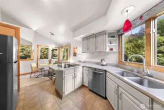 The bright kitchen and adjacent dining area are set against large picture windows overlooking dense trees offering the perfect mix of light and privacy.