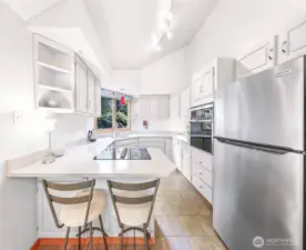 Oversized windows flood the kitchen with natural light and showcase the surrounding privacy of lush greenery.