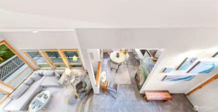 The soaring loft overlooks a light-filled great room, showcasing floor-to-ceiling windows and a seamless flow between dining, kitchen, and living spaces.