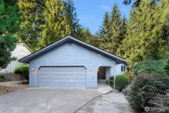 Framed by mature landscaping and lush evergreens, this inviting entry blends privacy and natural beauty with welcoming symmetry.