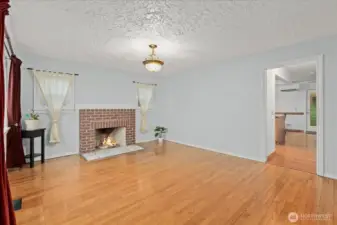 Warm hardwood floors and a brick fireplace create a warm focal point.
