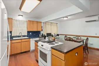 The kitchen features warm wood cabinetry, ample counter space, and a functional center island with extra storage.