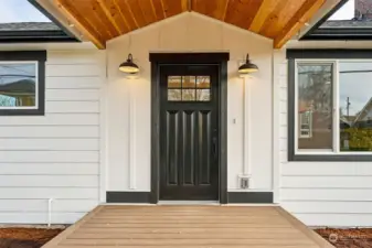 The brand new covered front porch sits high above the walkable sidewalk-lined street.