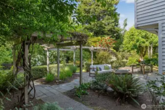 The practical and elegant backyard features a large level patio, mature plantings and charming garden features.