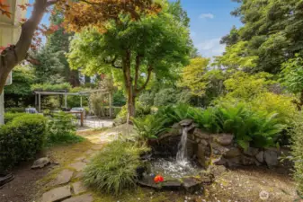 The practical and elegant backyard features a large level patio, mature plantings and charming garden features.