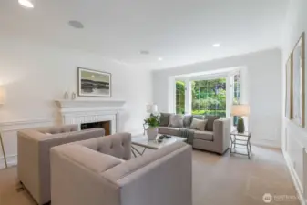 Bright living room with gas fireplace looking out to the manicured garden