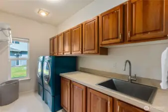 Large laundry room with beautiful wood cabinetry, plenty of counter space, a sink and hanging rack.  The washer and dryer convey with the home.