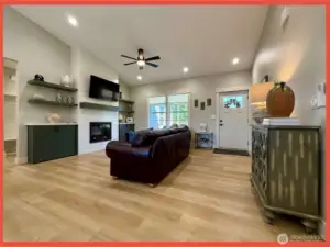 Enter into the 1,416 sf open concept plan into the great room with vaulted ceilings, fireplace wall flanked by shelves, and luxury vinyl plank flooring.