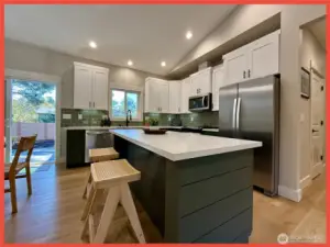 The kitchen features gorgeous cabinetry, stainless steel appliances, Quartz slab countertops, tiled backsplash, farm sink,  and island/breakfast bar.