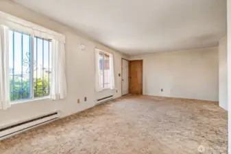 The living room is spacious and filled with light from the two generous windows. The white door shown is the front door. The wood door is where you enter the garage.