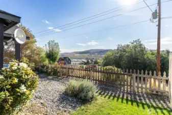 River and mountain views from your front yard, complete with a charming wooden fence and lush landscaping.
