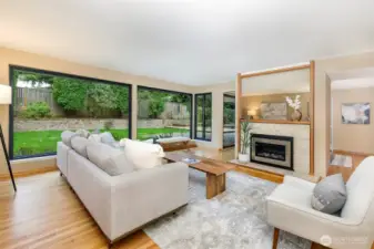 Open living room with hardwood floors, walls of windows, and garden views in Broadview Seattle home.