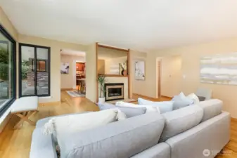 Open living room with hardwood floors, walls of windows, and garden views in Broadview Seattle home.