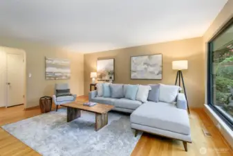 Open living room with hardwood floors, walls of windows, and garden views in Broadview Seattle home.