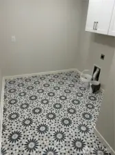 The laundry room is spacious with washer and dryer hookups, plenty of space for extra cabinets or shelving, and a new floor that adds a fun touch to laundry day.