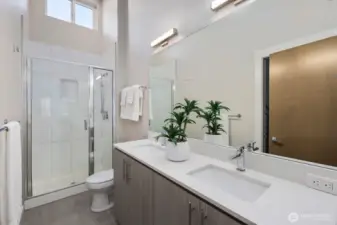 Primary bathroom with dual sinks and high ceilings.