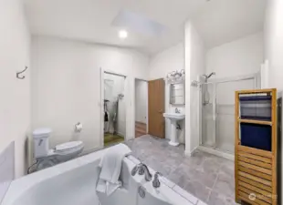 The  primary bathroom features a soaking tub, walk-in shower, and modern tile work. A spa-like experience awaits in this bright and tranquil space.