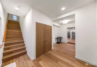 The main hallway offers an elegant transition between living spaces, featuring wide-plank wood floors and recessed lighting. The open layout connects seamlessly to the living room and dining area.