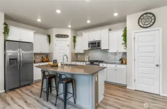 Beautiful white kitchen cabinets with grey quartz counter tops, tile backsplash.