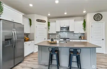 enough room for 4 or more at the counter - great gathering space. Stainless steel appliances compliment this light bright white & grey kitchen