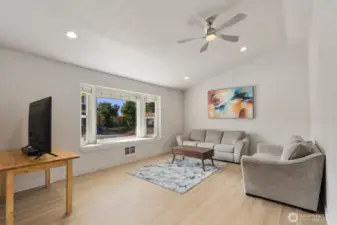 Living room with large front-facing windows, recessed lighting, ceiling fan, and updated flooring.