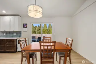 Dining area with updated flooring, modern light fixture, and sliding glass door to backyard.