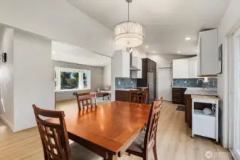 Open dining area with updated flooring, modern light fixture, and clear sightlines to remodeled kitchen and living room.