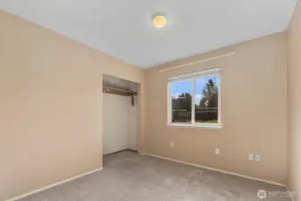 Bedroom with carpet flooring, open closet, and window overlooking fully fenced backyard