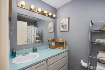 Bathroom with single-sink vanity, large wall mirror, overhead vanity lighting, and tub-shower combination