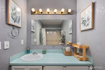 Full bathroom with extended counter, framed mirror, multi-light fixture, and tub-shower combination