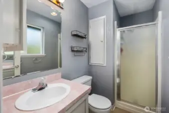 Bright full bath with a glass shower enclosure, frosted privacy window, and a spacious vanity counter for daily essentials