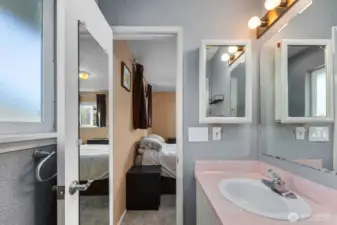 Functional bath with generous vanity space, strong overhead lighting, and easy flow to the adjacent bedroom