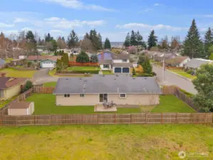 Drone view showcasing full fenced lot, patio area, and storage shed