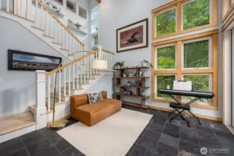 Notice full 2 story windows in the den/office. The stairs lead to the upper level primary suite. French doors lead outside to a large patio area with a water feature and fencing for pets