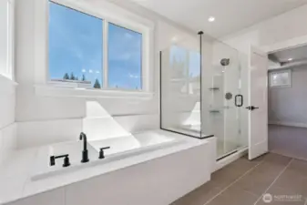 Inviting soaking tub and glass shower in primary bath.