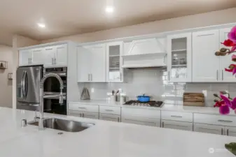 Pay attention to the wood wrapped vent hood, subway tile backsplash and gleaming white shaker cabinetry.