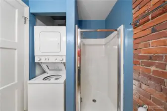 Other side of guest bathroom with stall shower and stacking washer-dryer.