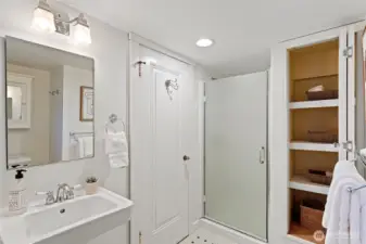 Lower level en-suite bathroom features hex tile flooring, pedestal sink, medicine chest and opening window to side yard.