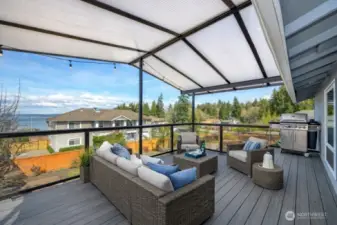 The ultimate outdoor retreat! This expansive, covered dream deck offers a seamless transition from the great room for year-round entertaining. Whether hosting a summer cookout or enjoying a quiet rainy evening, the glass railings ensure your views of the Sound and Hat Island remain completely unobstructed.