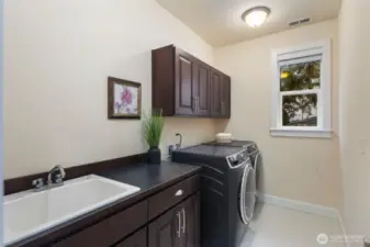 Upper level laundry room with side-by-side washer and dryer, utility sink and plenty of storage.