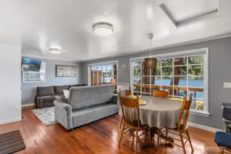 Dining area with round table, chairs, and large windows offering natural light.